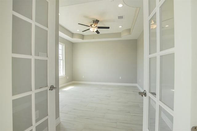 unfurnished room with french doors, a raised ceiling, and ceiling fan