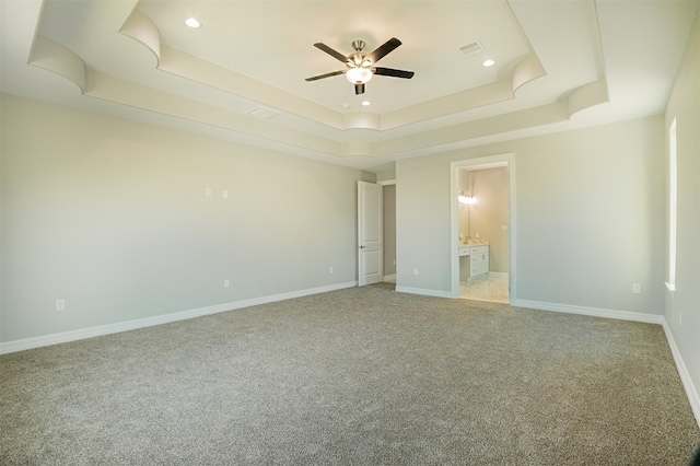 unfurnished bedroom with connected bathroom, light colored carpet, a raised ceiling, and ceiling fan