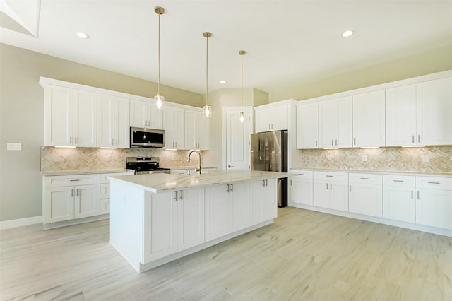 kitchen with white cabinets, decorative backsplash, a kitchen island with sink, and appliances with stainless steel finishes