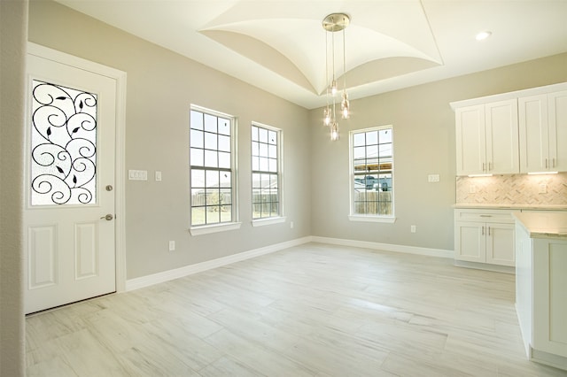 unfurnished dining area with light wood-type flooring and vaulted ceiling