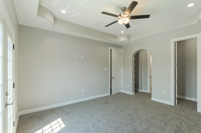 unfurnished bedroom with a tray ceiling, ceiling fan, and light carpet