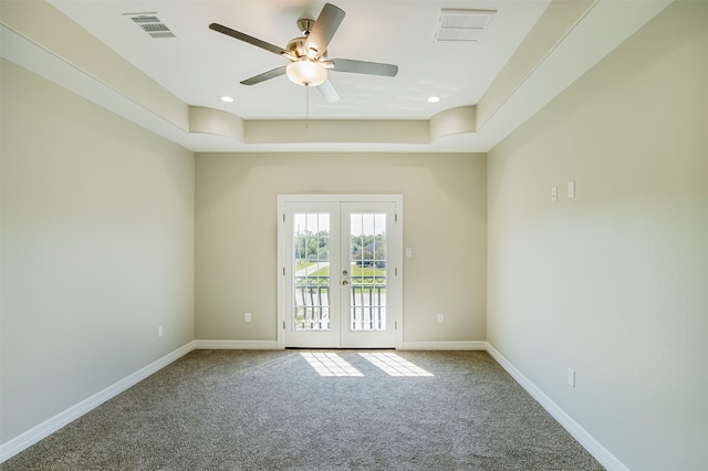 spare room featuring a tray ceiling, ceiling fan, french doors, and carpet