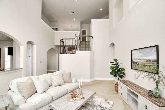 carpeted living room featuring a towering ceiling