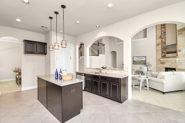 kitchen featuring dark brown cabinetry, sink, stainless steel dishwasher, pendant lighting, and a fireplace