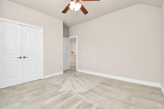 unfurnished bedroom with light carpet, a closet, vaulted ceiling, and ceiling fan