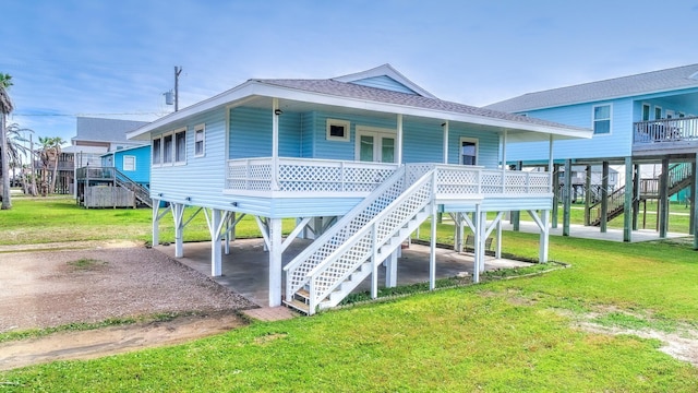 rear view of property with a yard, covered porch, and stairs