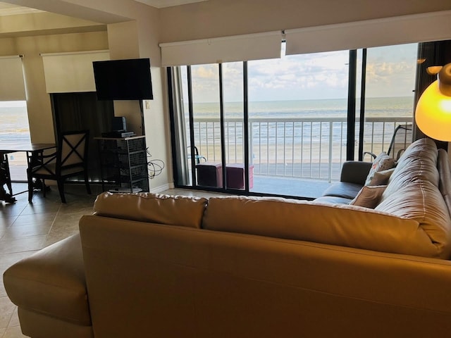 living room featuring a water view, light tile patterned flooring, and a healthy amount of sunlight