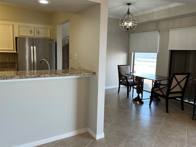 kitchen featuring decorative backsplash, an inviting chandelier, light stone countertops, light tile patterned floors, and stainless steel fridge