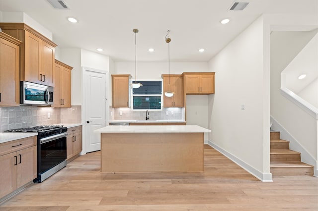 kitchen with appliances with stainless steel finishes, light hardwood / wood-style floors, a kitchen island, and sink