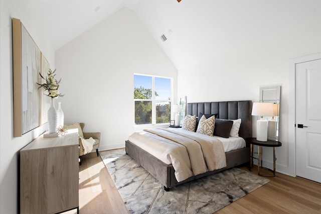 bedroom featuring high vaulted ceiling and light hardwood / wood-style flooring