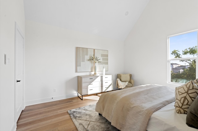 bedroom featuring high vaulted ceiling and light hardwood / wood-style floors