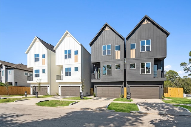 multi unit property featuring board and batten siding, fence, driveway, and a garage