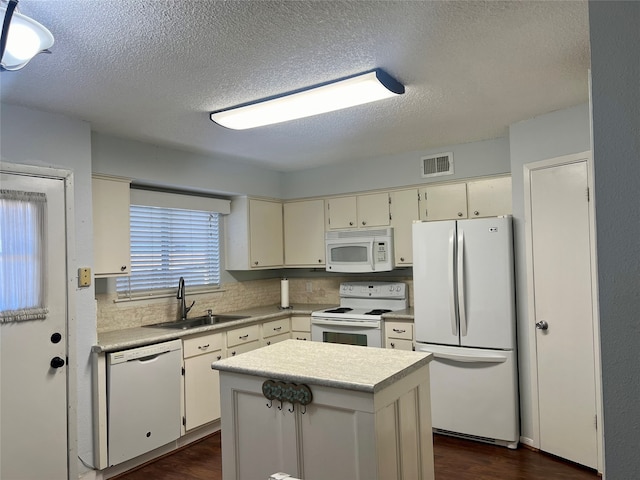 kitchen featuring sink, white appliances, dark wood-type flooring, and a textured ceiling