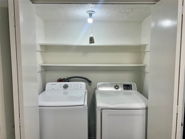 laundry room featuring washing machine and clothes dryer and a textured ceiling