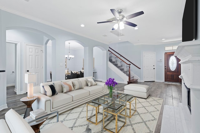 living room featuring ceiling fan with notable chandelier, light hardwood / wood-style floors, and crown molding