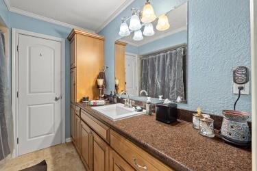 bathroom featuring crown molding, vanity, and a chandelier