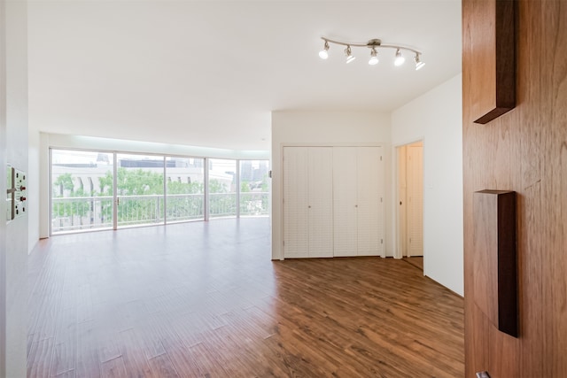 spare room with track lighting and wood-type flooring