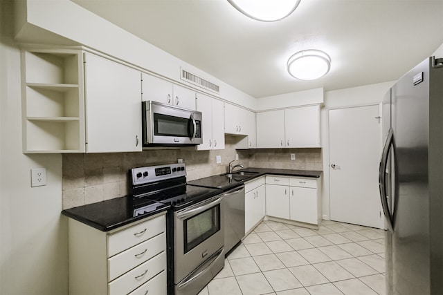 kitchen with backsplash, stainless steel appliances, white cabinetry, sink, and light tile patterned floors