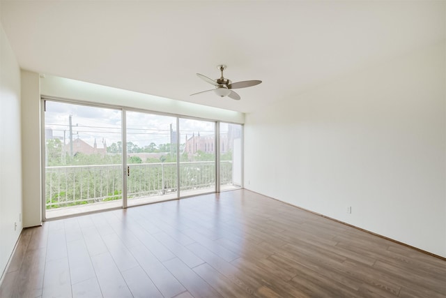 empty room featuring light wood-type flooring, expansive windows, ceiling fan, and plenty of natural light