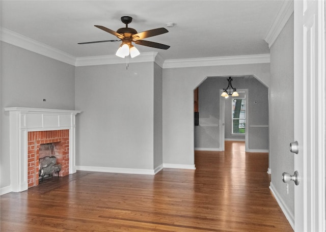 unfurnished living room with ornamental molding, a brick fireplace, dark hardwood / wood-style floors, and ceiling fan with notable chandelier