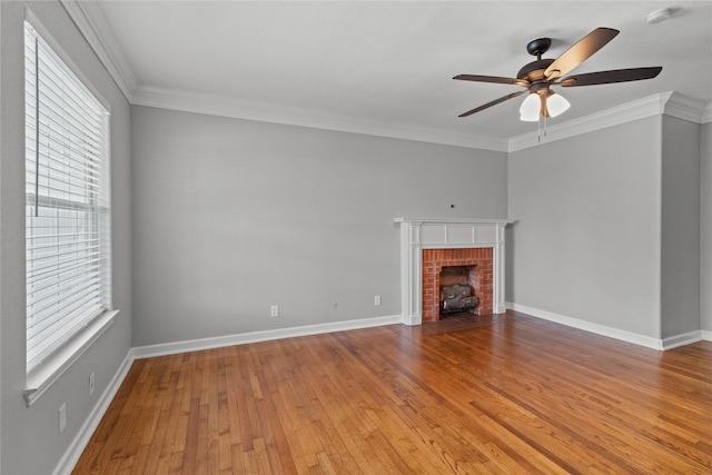 unfurnished living room featuring wood-type flooring, ornamental molding, ceiling fan, and a fireplace