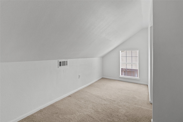 bonus room featuring carpet flooring, vaulted ceiling, and a textured ceiling