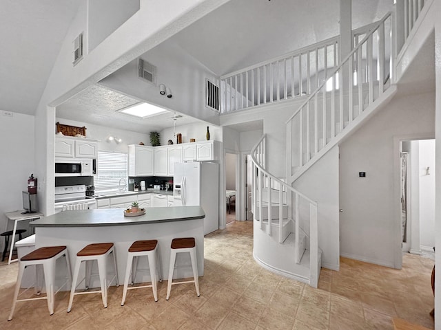 kitchen featuring white cabinetry, high vaulted ceiling, light tile patterned flooring, and white appliances