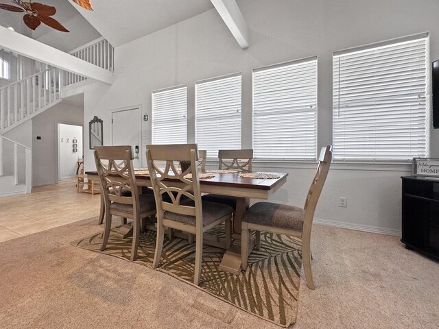 carpeted dining room featuring ceiling fan, high vaulted ceiling, and beamed ceiling