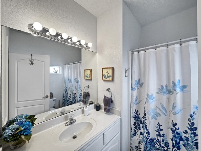 bathroom with a textured ceiling, toilet, and vanity