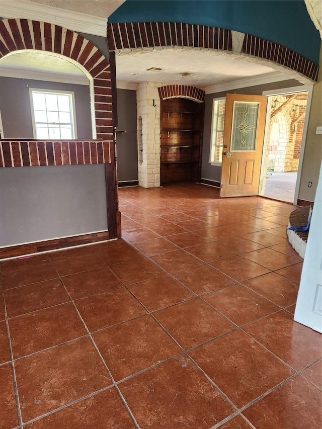 foyer featuring dark tile patterned flooring and crown molding