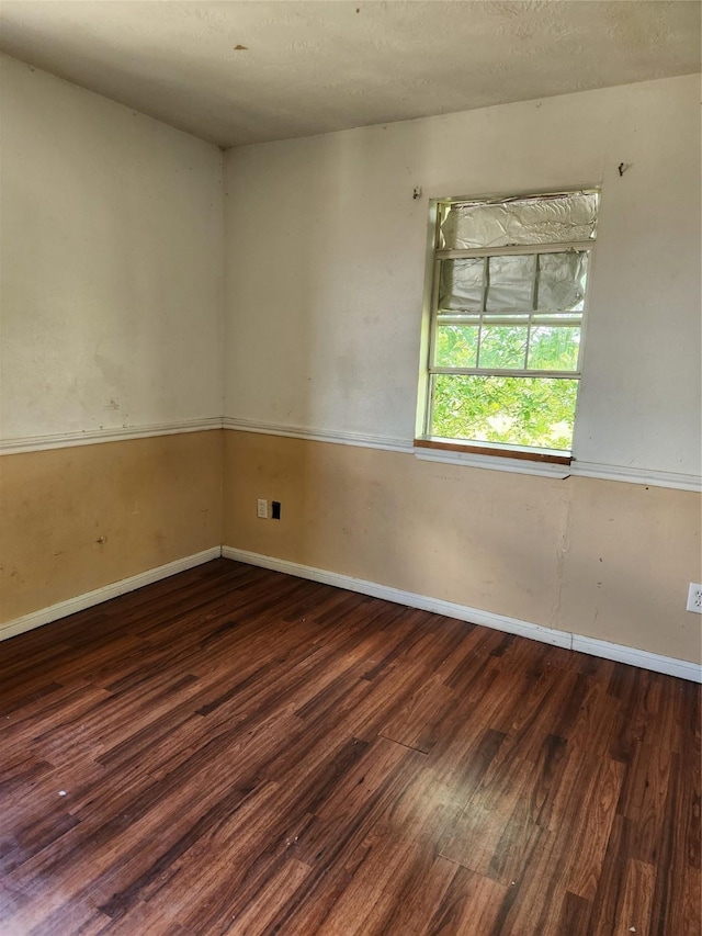 unfurnished room with dark wood-type flooring and baseboards