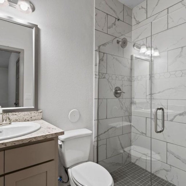 bathroom with an enclosed shower, vanity, and toilet