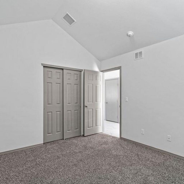 unfurnished bedroom featuring vaulted ceiling, a closet, and carpet flooring