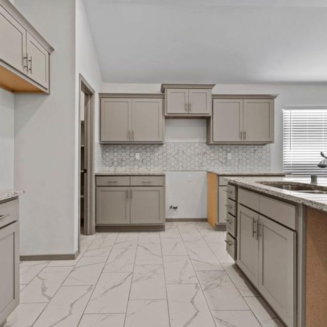 kitchen with light stone counters, gray cabinets, and decorative backsplash