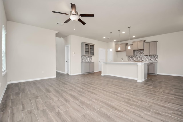 unfurnished living room featuring visible vents, ceiling fan, light wood-style flooring, and baseboards