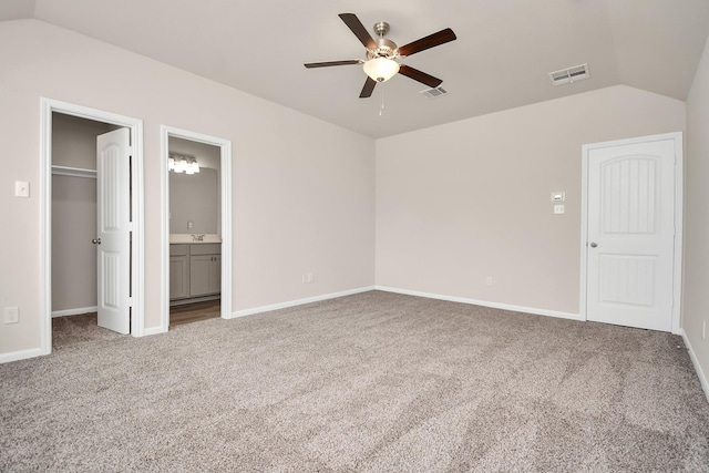 unfurnished bedroom featuring vaulted ceiling, carpet flooring, visible vents, and a walk in closet