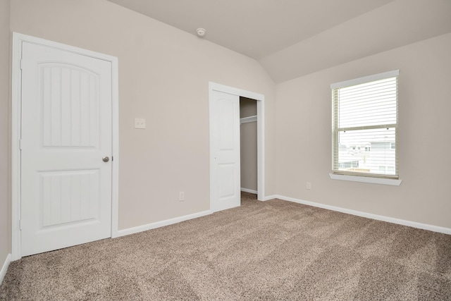 unfurnished bedroom with carpet floors, lofted ceiling, a closet, and baseboards