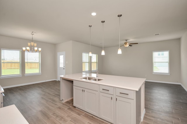 kitchen with open floor plan, light countertops, a sink, and a center island with sink