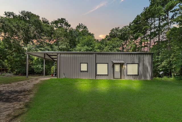 outdoor structure at dusk featuring a lawn and a carport