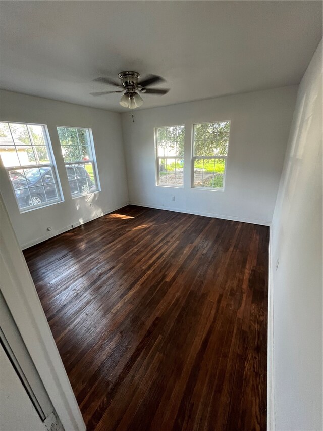 spare room with dark hardwood / wood-style floors, a wealth of natural light, and ceiling fan