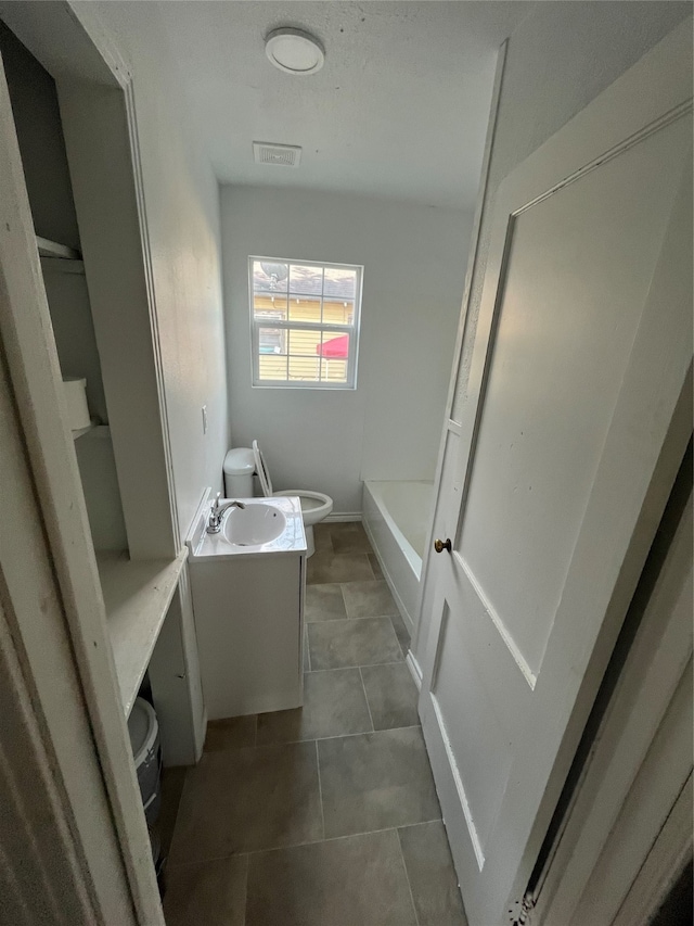 bathroom with vanity, tile patterned flooring, toilet, and a bath