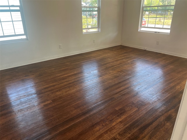 empty room with plenty of natural light and dark hardwood / wood-style floors