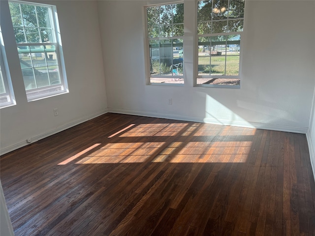 empty room with plenty of natural light and dark hardwood / wood-style flooring