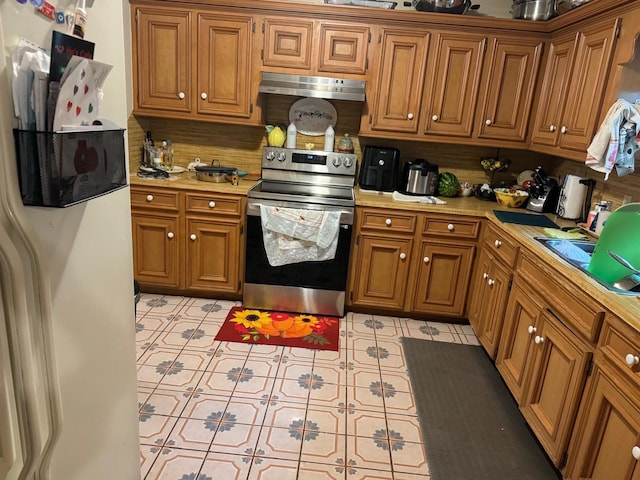 kitchen featuring sink, white fridge with ice dispenser, decorative backsplash, stainless steel range with electric stovetop, and light tile patterned floors