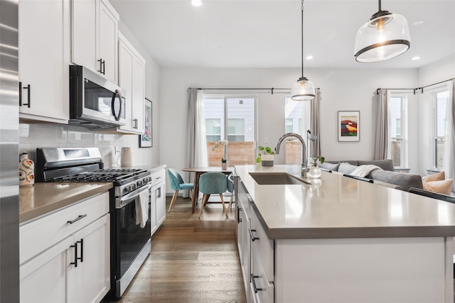 kitchen with tasteful backsplash, dark hardwood / wood-style floors, an island with sink, and stainless steel appliances