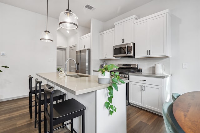 kitchen featuring decorative backsplash, pendant lighting, dark hardwood / wood-style flooring, a center island with sink, and stainless steel appliances