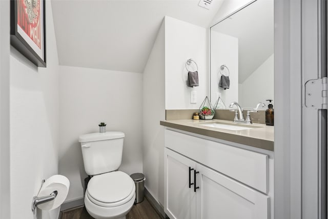 bathroom with toilet, lofted ceiling, vanity, and hardwood / wood-style flooring