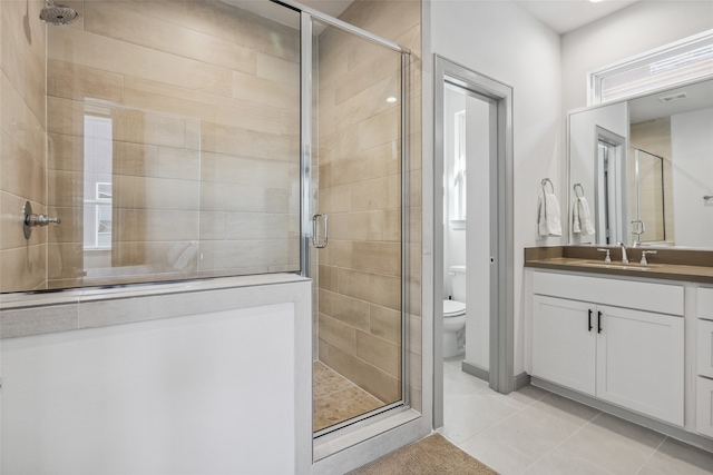 bathroom with tile patterned flooring, a shower with door, vanity, and toilet