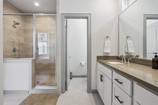 bathroom with a shower with door, toilet, vanity, and tile patterned floors