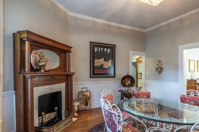 dining space featuring a tiled fireplace, hardwood / wood-style floors, and ornamental molding